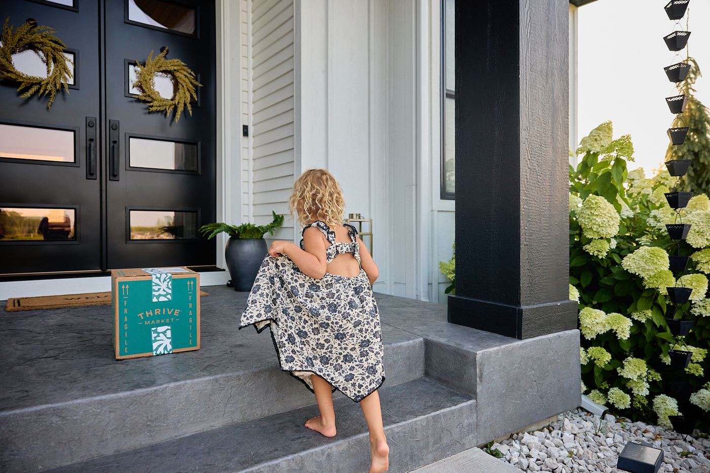 Emery running up the front porch steps to a Thrive Market delivery box